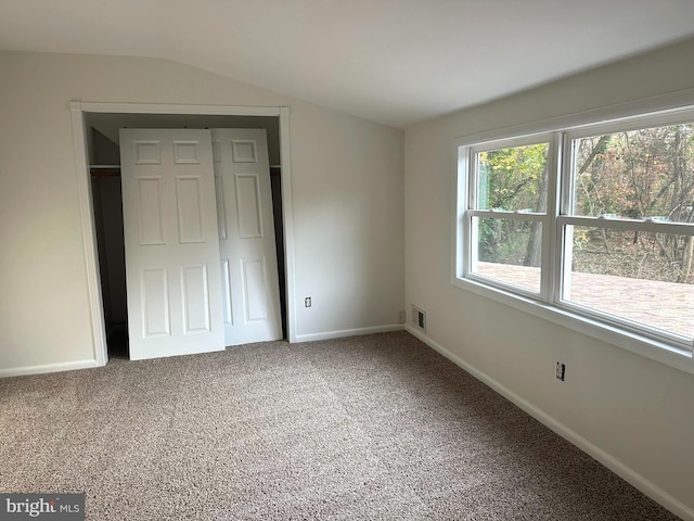 unfurnished bedroom featuring a closet, lofted ceiling, and carpet flooring