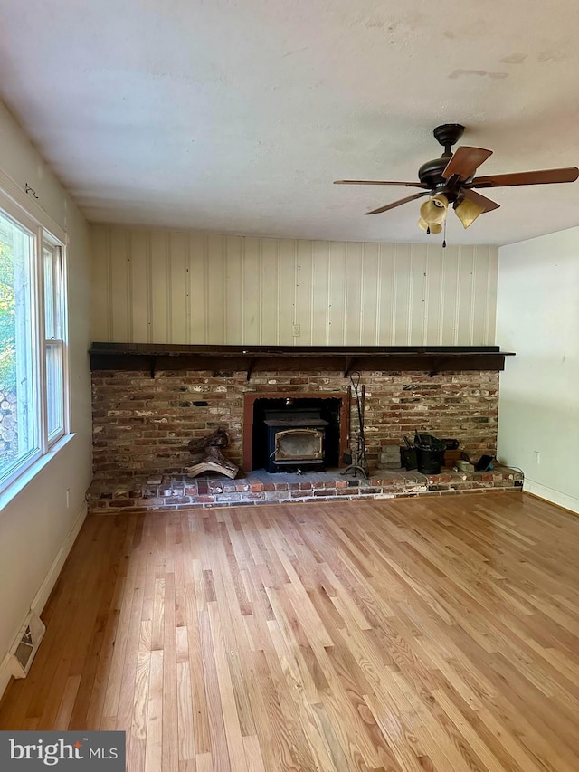 unfurnished living room with ceiling fan, wood-type flooring, and a brick fireplace