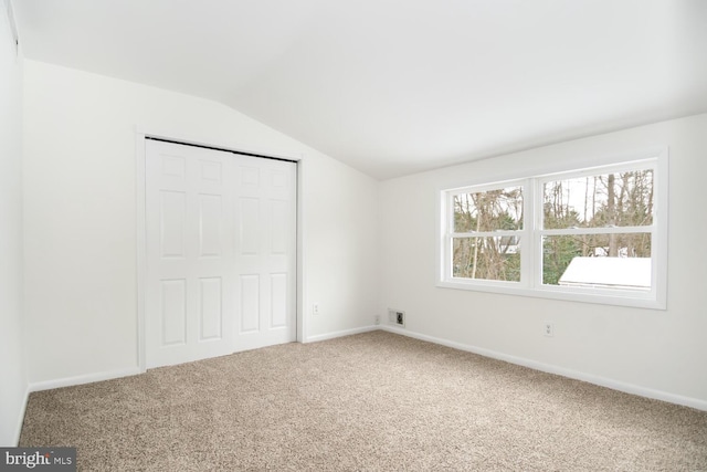 unfurnished bedroom with lofted ceiling, carpet flooring, and a closet