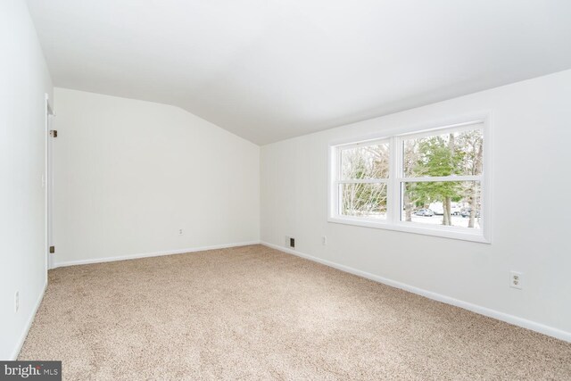 carpeted spare room featuring vaulted ceiling