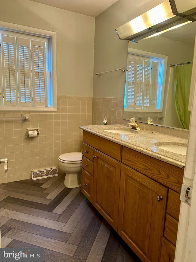 bathroom with vanity, parquet flooring, tile walls, and toilet