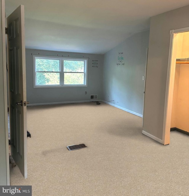 interior space featuring light carpet, a walk in closet, and a closet