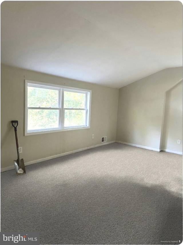 carpeted empty room with vaulted ceiling