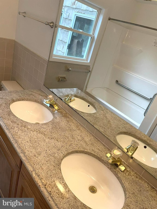 bathroom with tile walls, toilet, and vanity