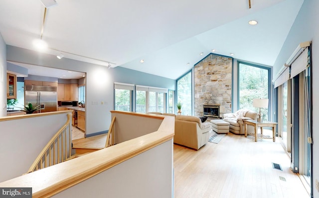 living room with plenty of natural light, a fireplace, lofted ceiling, and light wood-style floors