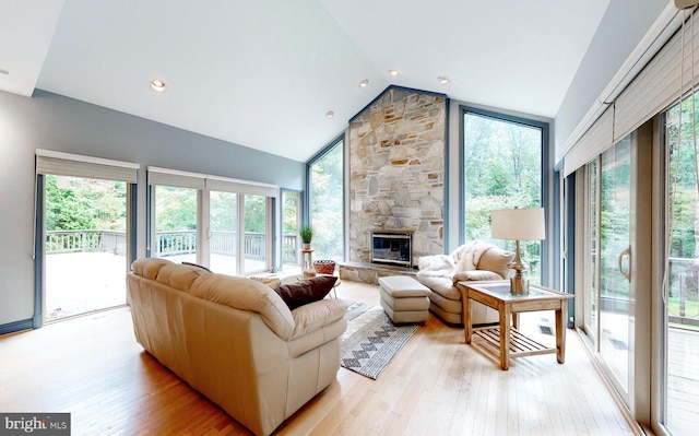 living area with plenty of natural light, a fireplace, light wood finished floors, and high vaulted ceiling