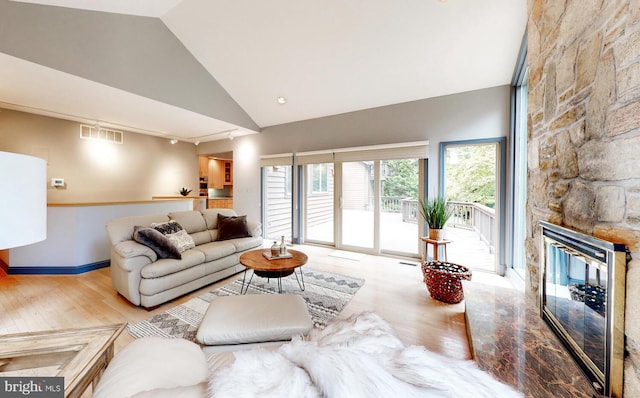 living room featuring a fireplace, high vaulted ceiling, and light hardwood / wood-style floors