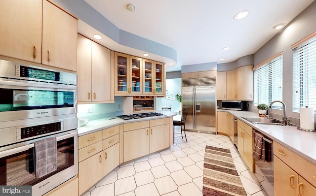 kitchen featuring light brown cabinetry, appliances with stainless steel finishes, light countertops, and a sink