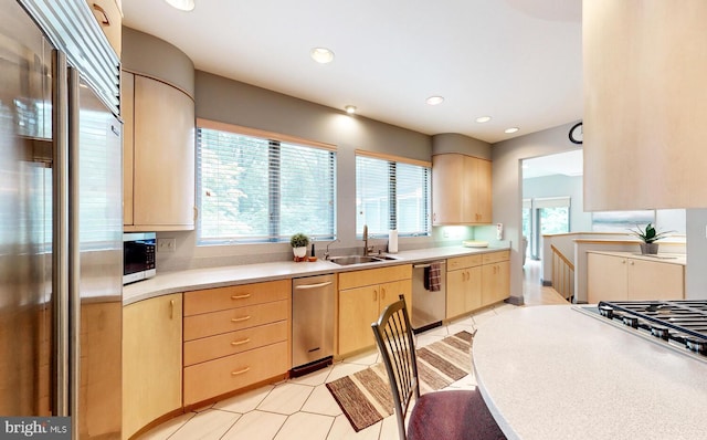 kitchen featuring light tile patterned floors, a sink, stainless steel appliances, light countertops, and light brown cabinetry