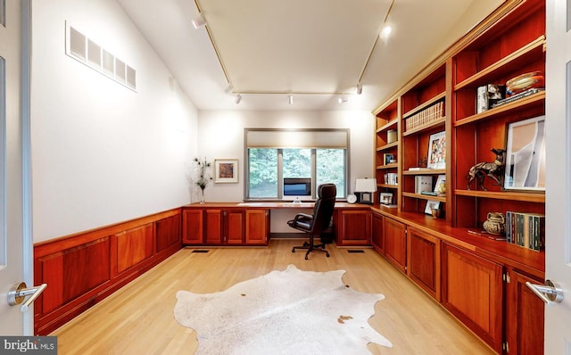 office area featuring a wainscoted wall, light wood-type flooring, visible vents, and built in study area