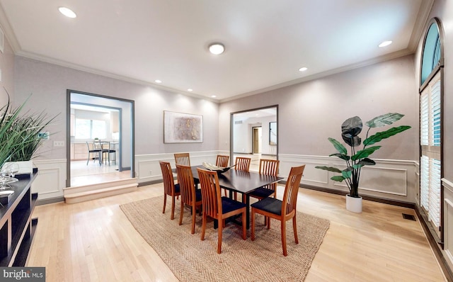 dining room with crown molding and light hardwood / wood-style flooring