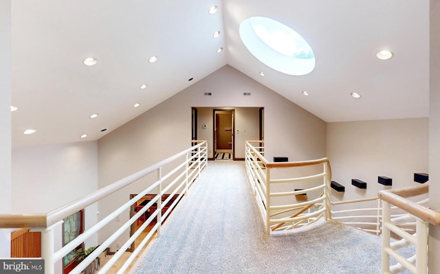 corridor featuring light colored carpet and vaulted ceiling with skylight