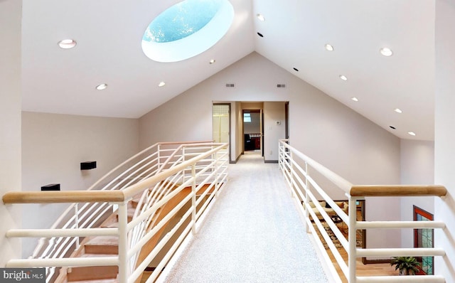 hall featuring lofted ceiling with skylight and light carpet