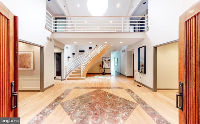 entryway featuring a towering ceiling and light hardwood / wood-style flooring