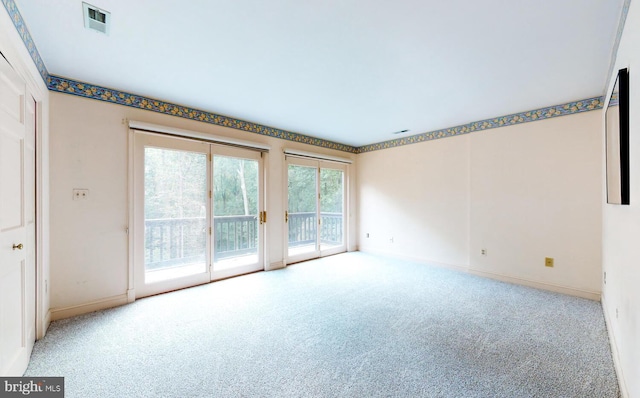 empty room with carpet, visible vents, and baseboards