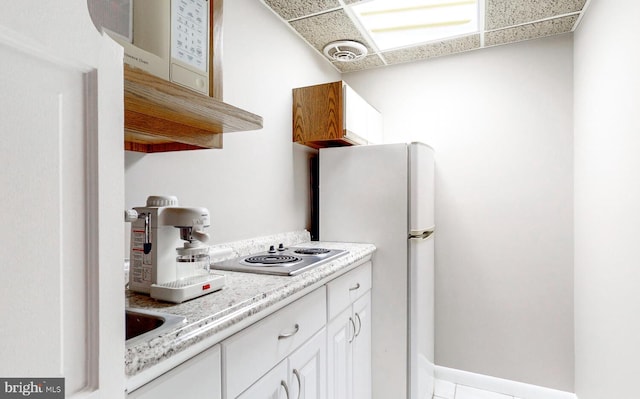 kitchen featuring open shelves, stainless steel electric cooktop, freestanding refrigerator, white cabinets, and light countertops