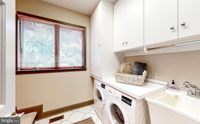 washroom with visible vents, baseboards, washer and dryer, cabinet space, and a sink