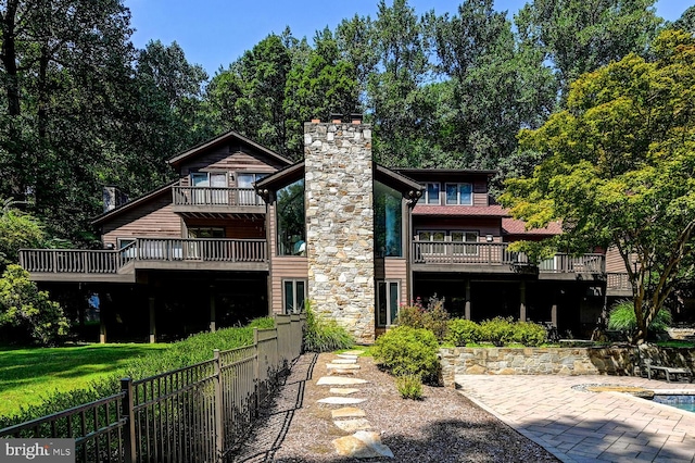 back of property with fence, a lawn, and a chimney