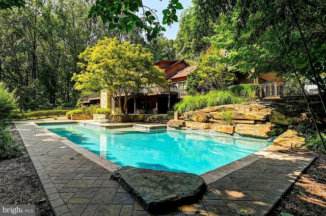 outdoor pool with a patio, a deck, and fence