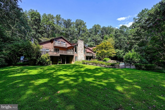 rear view of property with a deck, a lawn, and a chimney