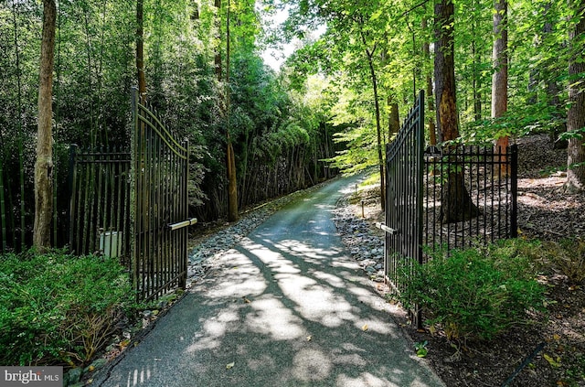 view of gate featuring a forest view and fence