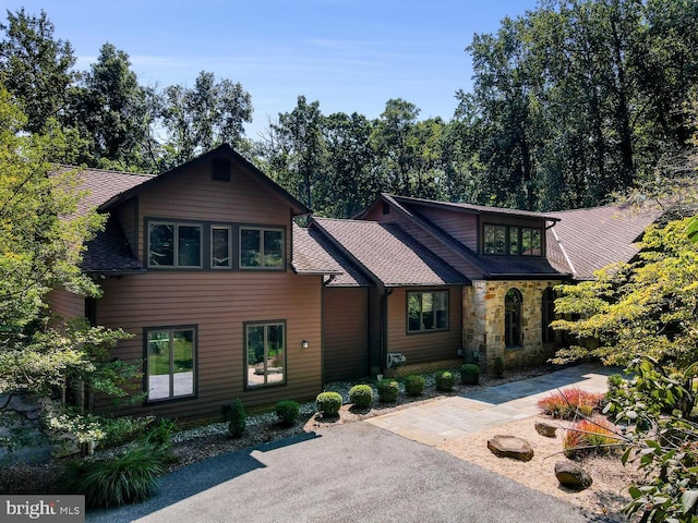 view of front of home with stone siding and roof with shingles