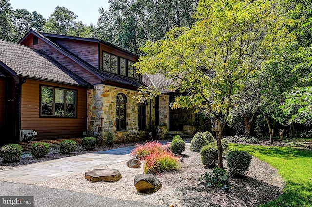 view of front of property with stone siding and roof with shingles