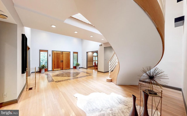 entryway with recessed lighting, baseboards, a towering ceiling, and light wood finished floors