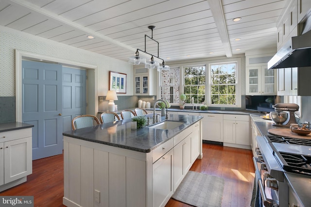 kitchen featuring white cabinets, hanging light fixtures, an island with sink, and sink