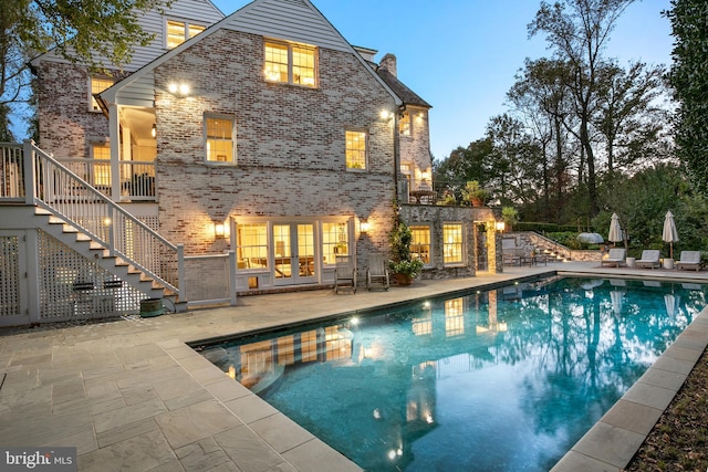 back house at dusk featuring a patio and french doors