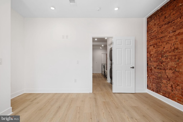 empty room featuring light hardwood / wood-style floors and brick wall