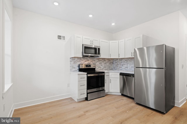 kitchen featuring tasteful backsplash, stainless steel appliances, light hardwood / wood-style floors, and white cabinetry