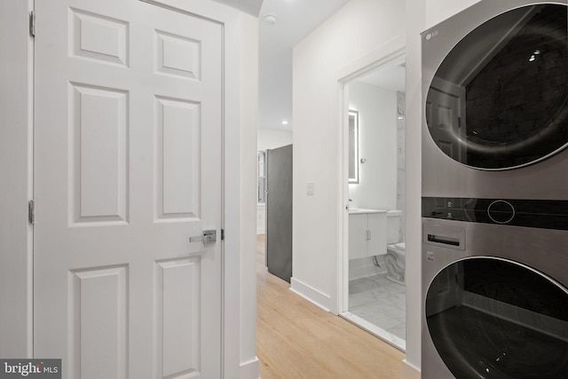 laundry area with stacked washer / dryer and light hardwood / wood-style floors