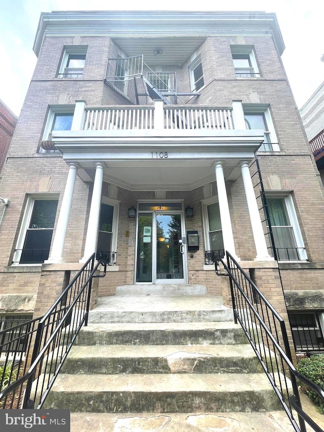 property entrance with covered porch and a balcony