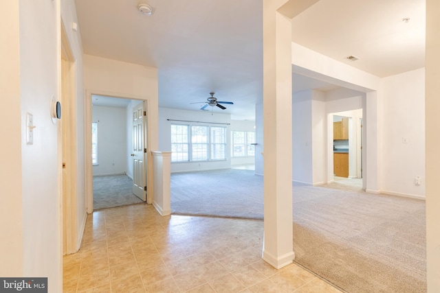 unfurnished living room featuring ceiling fan and light carpet