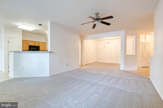 unfurnished living room featuring light colored carpet and ceiling fan with notable chandelier