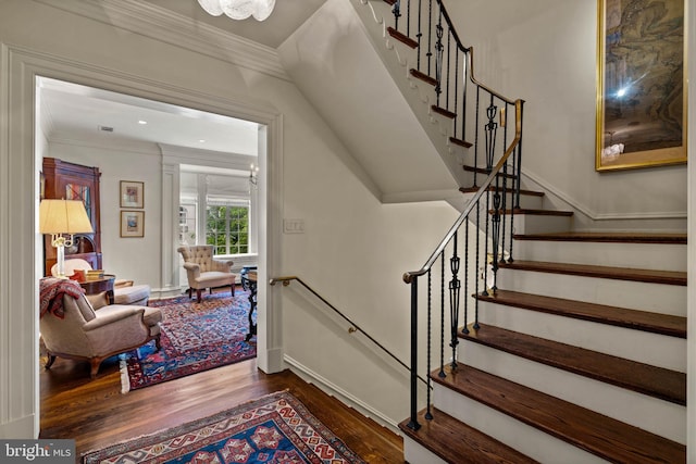 staircase featuring baseboards, wood finished floors, and crown molding