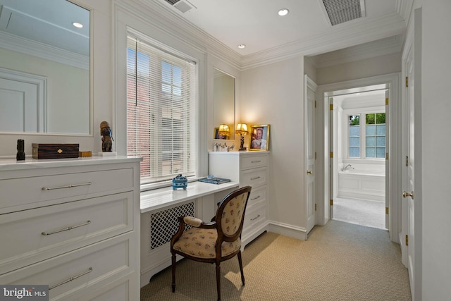 office space with visible vents, ornamental molding, built in desk, and light colored carpet