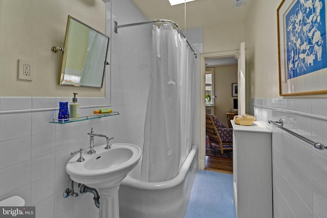 bathroom with visible vents, shower / bath combo with shower curtain, and tile walls