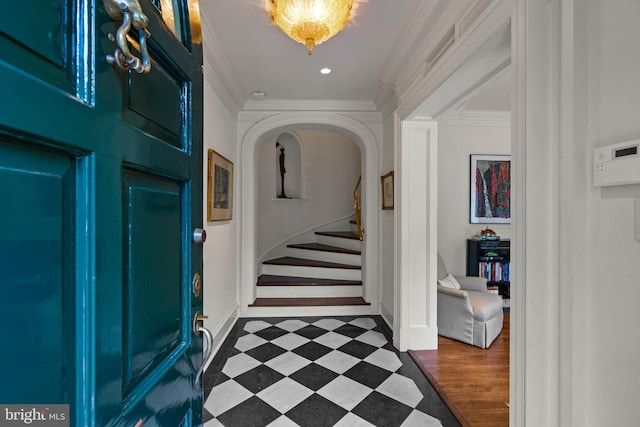 entryway featuring arched walkways, dark floors, baseboards, stairs, and ornamental molding