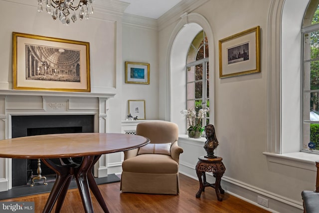 sitting room with dark wood-style floors, a fireplace, ornamental molding, a chandelier, and baseboards