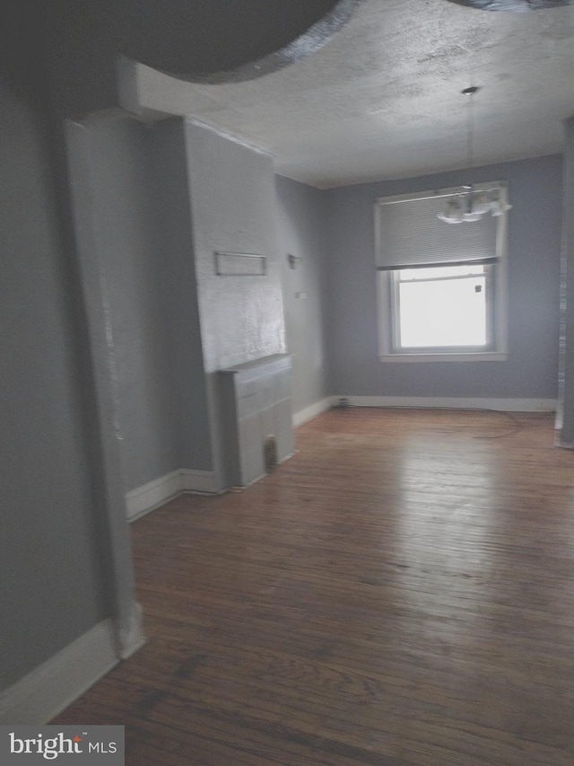 unfurnished living room with a textured ceiling and dark hardwood / wood-style floors