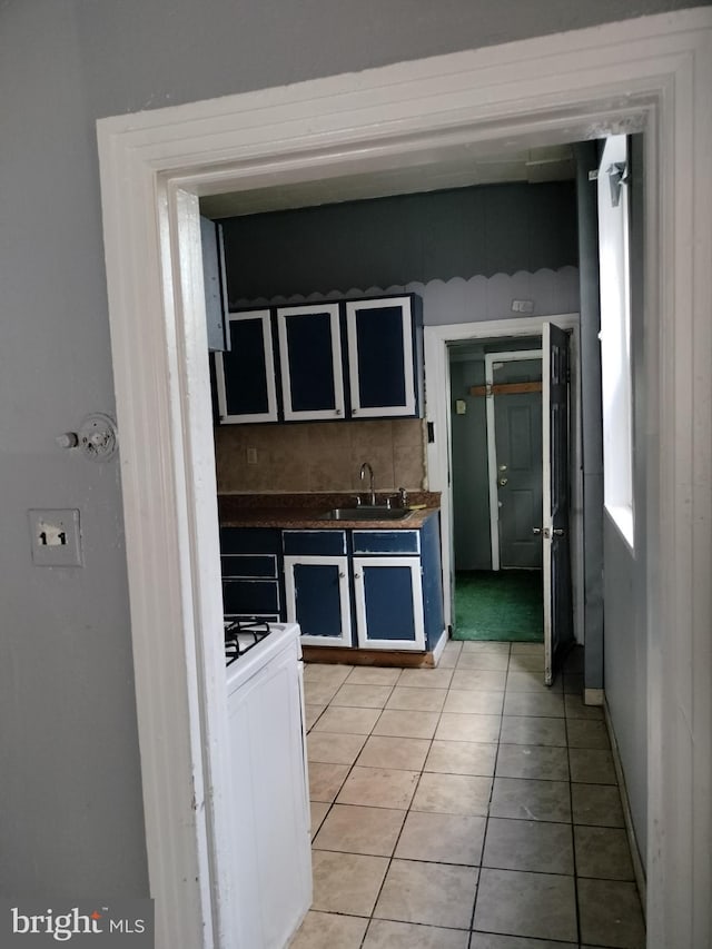 kitchen with sink, light tile patterned floors, white gas range oven, and tasteful backsplash