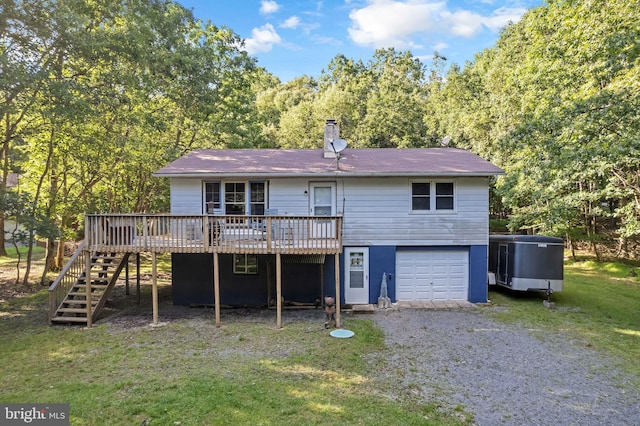 back of property featuring a wooden deck, a garage, and a yard