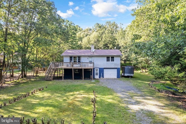 back of property featuring a lawn, a garage, and a wooden deck