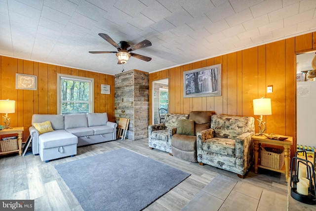 living room with ceiling fan, wood walls, and light hardwood / wood-style floors