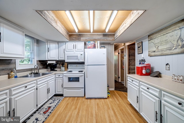 kitchen with white appliances, white cabinets, a tray ceiling, light hardwood / wood-style flooring, and sink