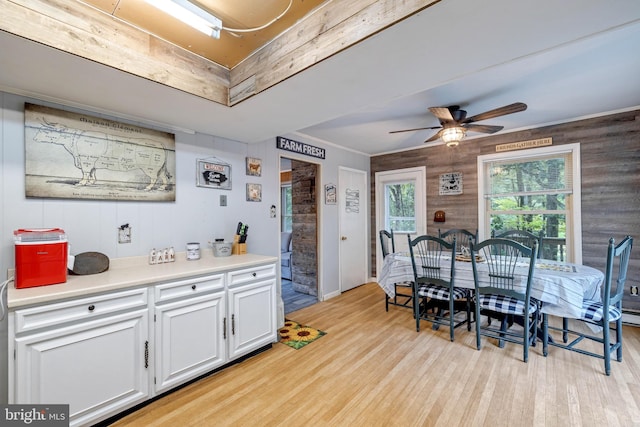 kitchen featuring white cabinets, wooden walls, light wood-type flooring, and ceiling fan