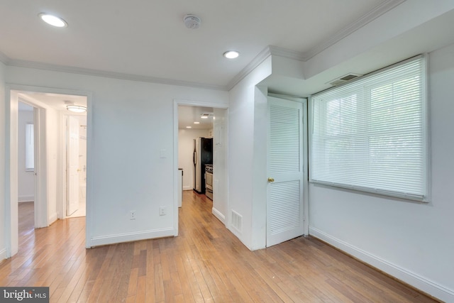 unfurnished room with light wood finished floors, ornamental molding, visible vents, and baseboards