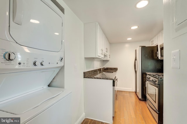 clothes washing area with recessed lighting, light wood-style floors, stacked washer / dryer, a sink, and laundry area